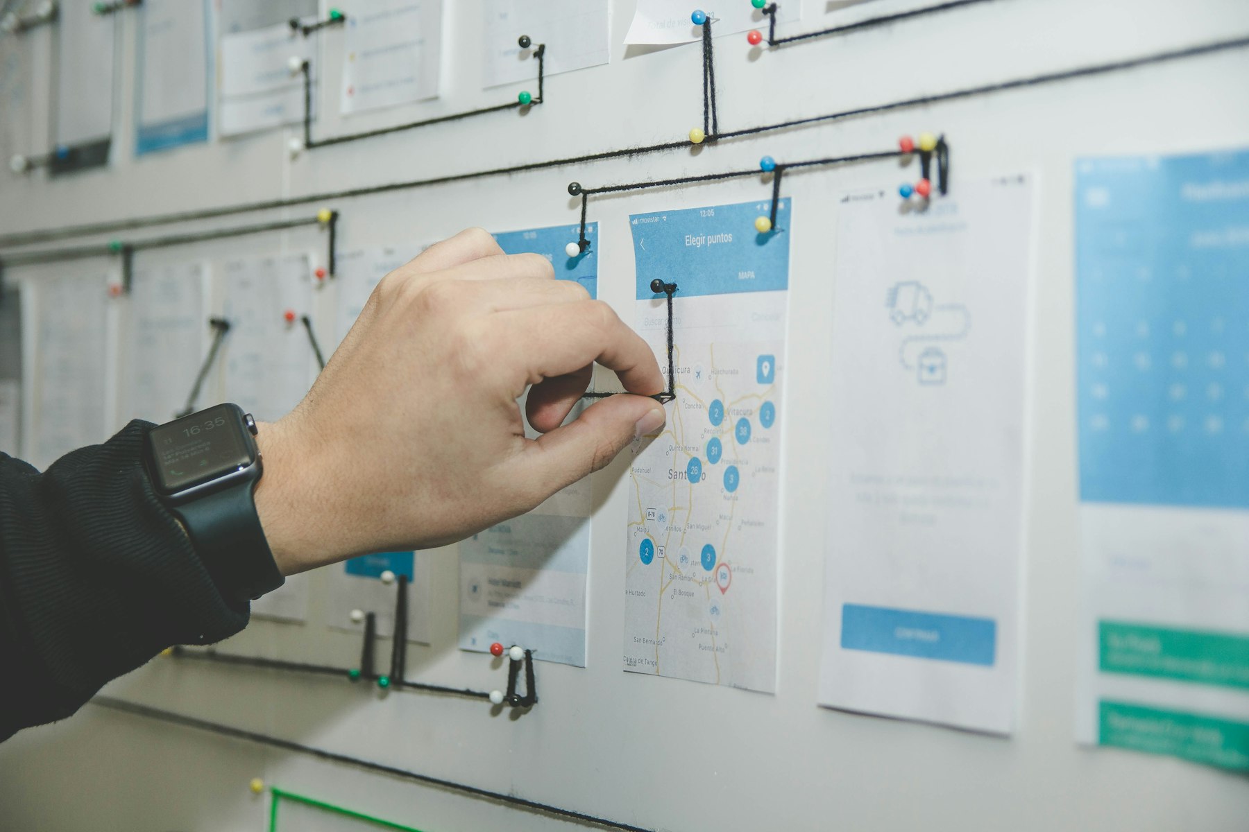 A hand pinning connections on a wall of system diagrams